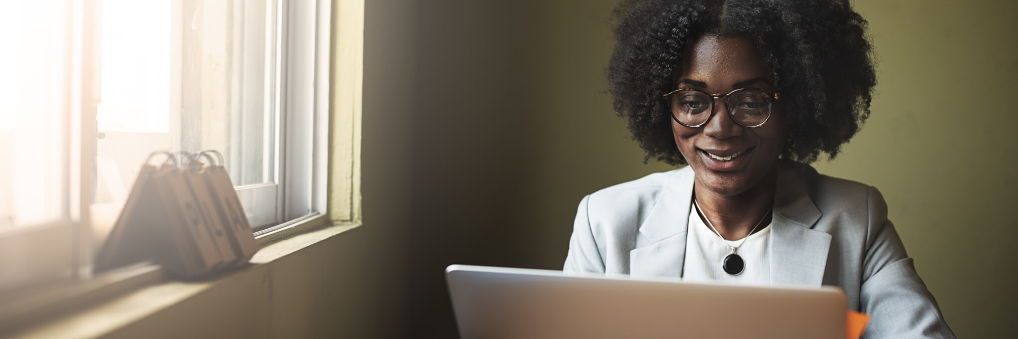 business woman smiling at laptop while looking at dental plans