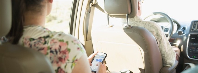 girl on her phone in backseat of a car