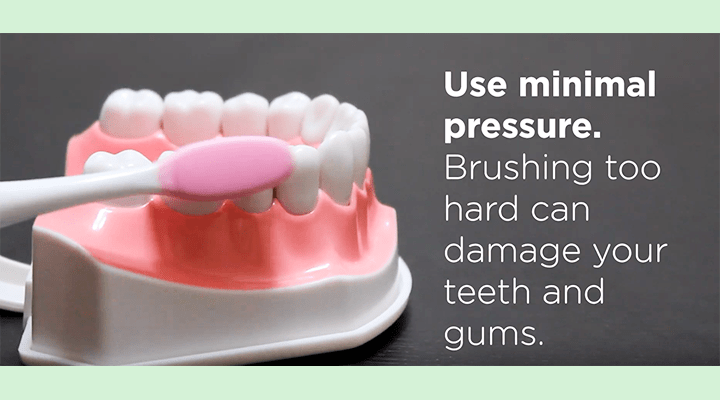 toothbrush brushing fake teeth, overlay: use minimal pressure. brushing too hard can damage your teeth and gums.