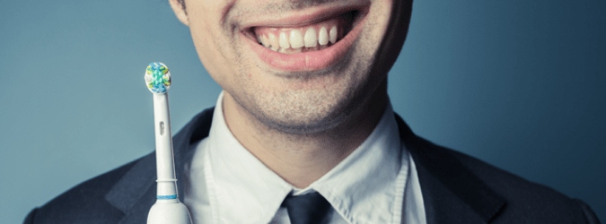 man smiling holding electric toothbrush