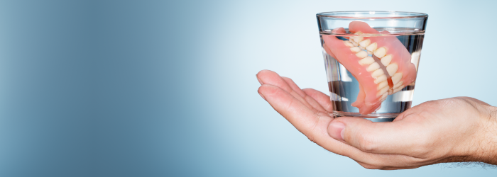 hand holding dentures in cup
