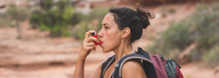 female hiker using an inhaler