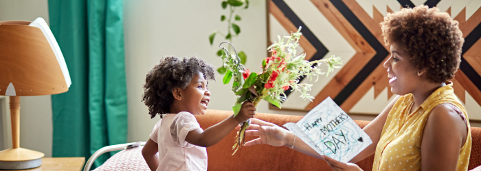 daughter giving flowers and card to mother