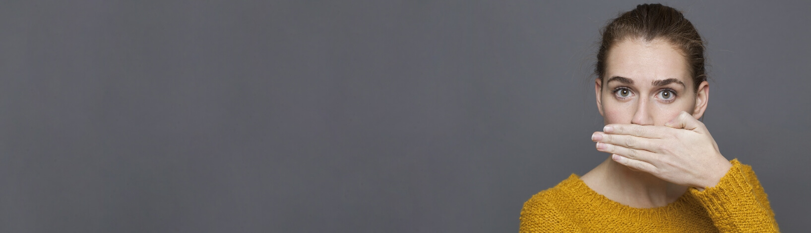 woman with bad breath covering her mouth