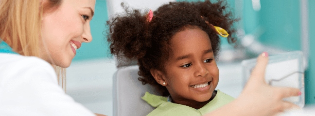 dentist showing young girl her teeth