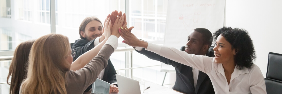 happy employees sitting in a circle giving a high five