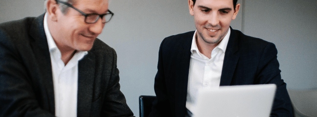 two men looking at a laptop