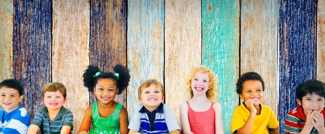 small smiling children lined up in front of a colorful wall