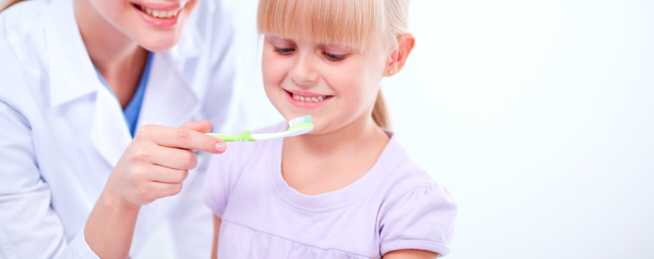 dentist brushing young girl's teeth