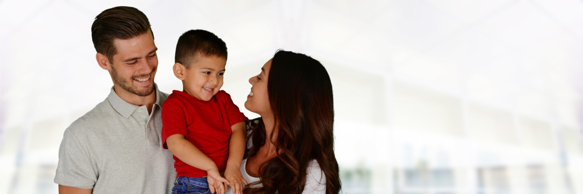 father holding son and mother smiling at son