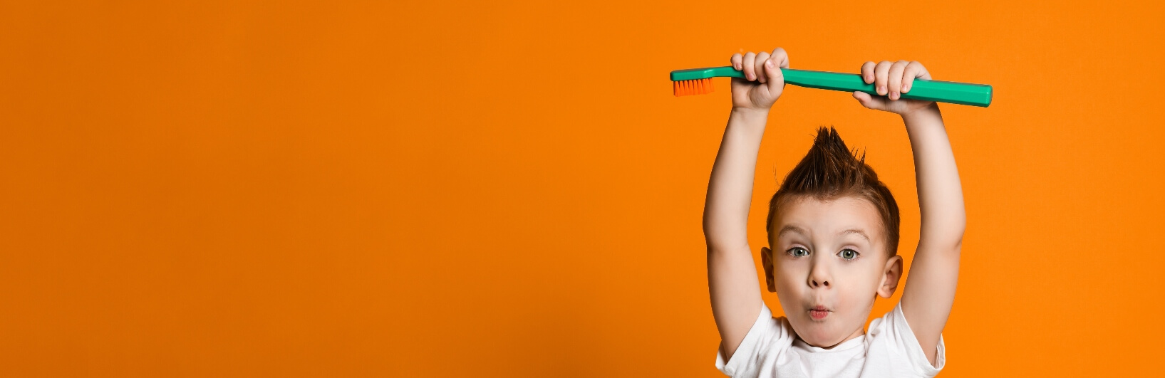 boy holding up a giant green toothbrush