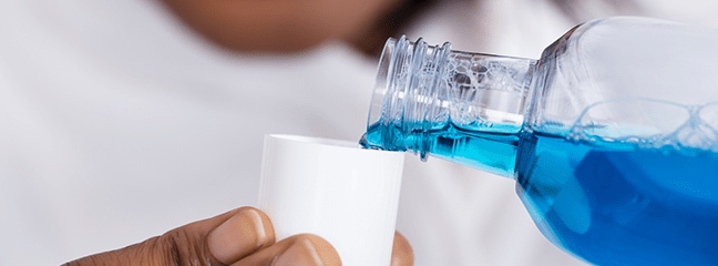 close up of blue mouthwash being poured into cap