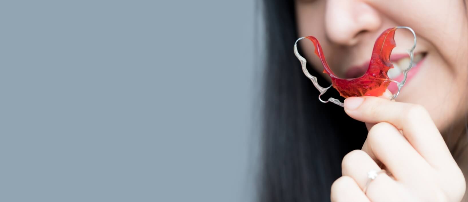 girl holding red retainer from orthodontist